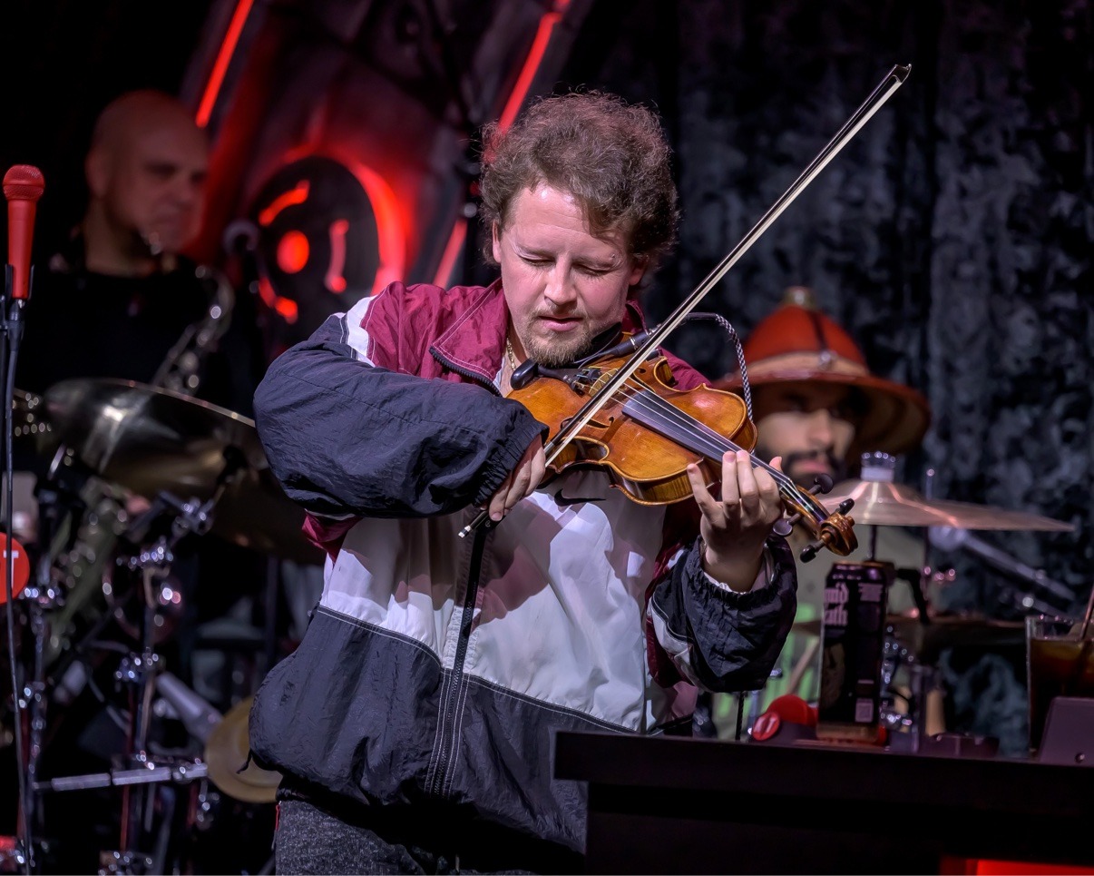 Jake Kennedy playing violin under red stage lights