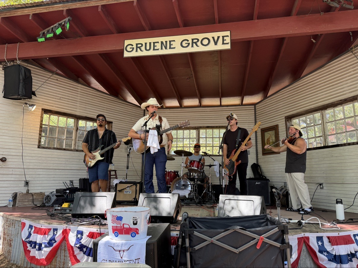 Jake playing fiddle with a full band on the outdoor stage at Gruene Grove