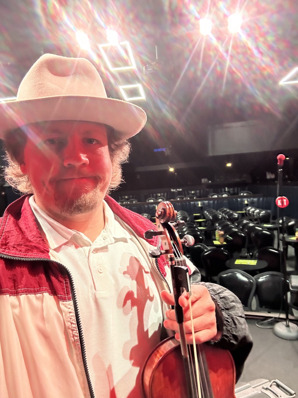 Jake holding his violin at a comedy club venue