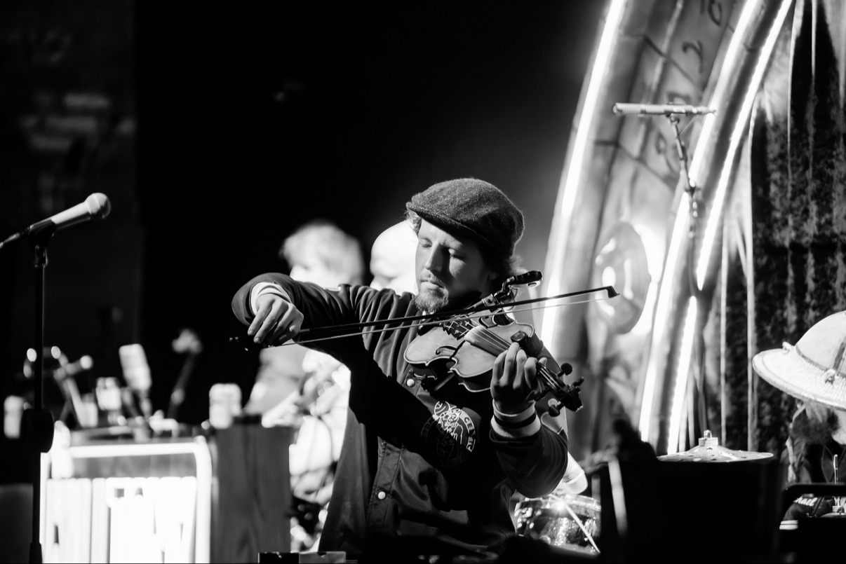 Jake playing violin onstage in black and white