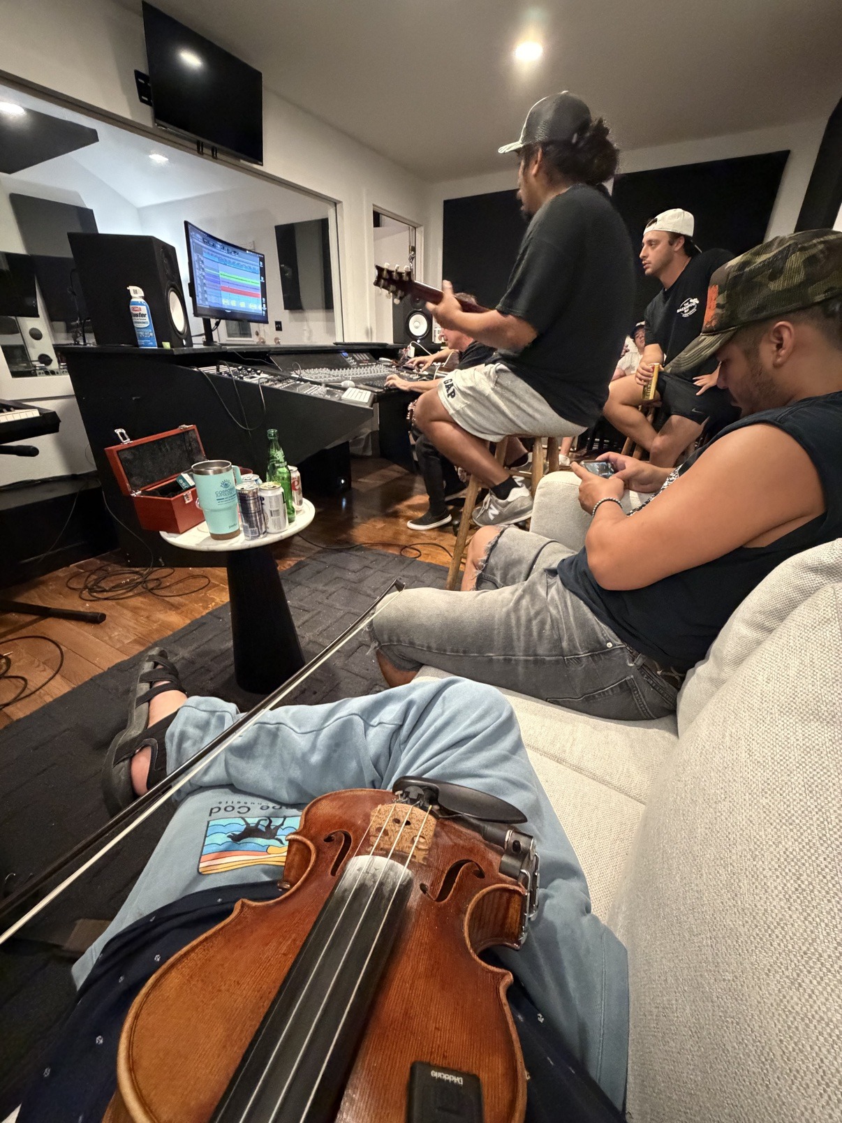 Jake in a studio control room with his violin resting on his lap