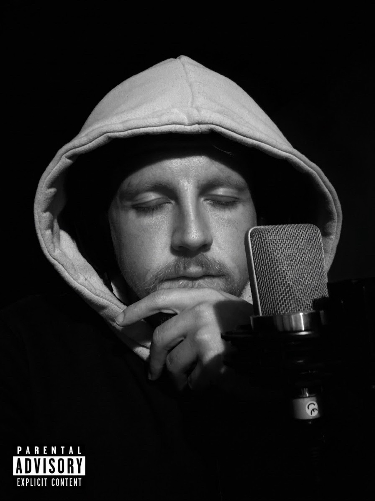Black-and-white portrait of Jake in a hoodie at a studio microphone