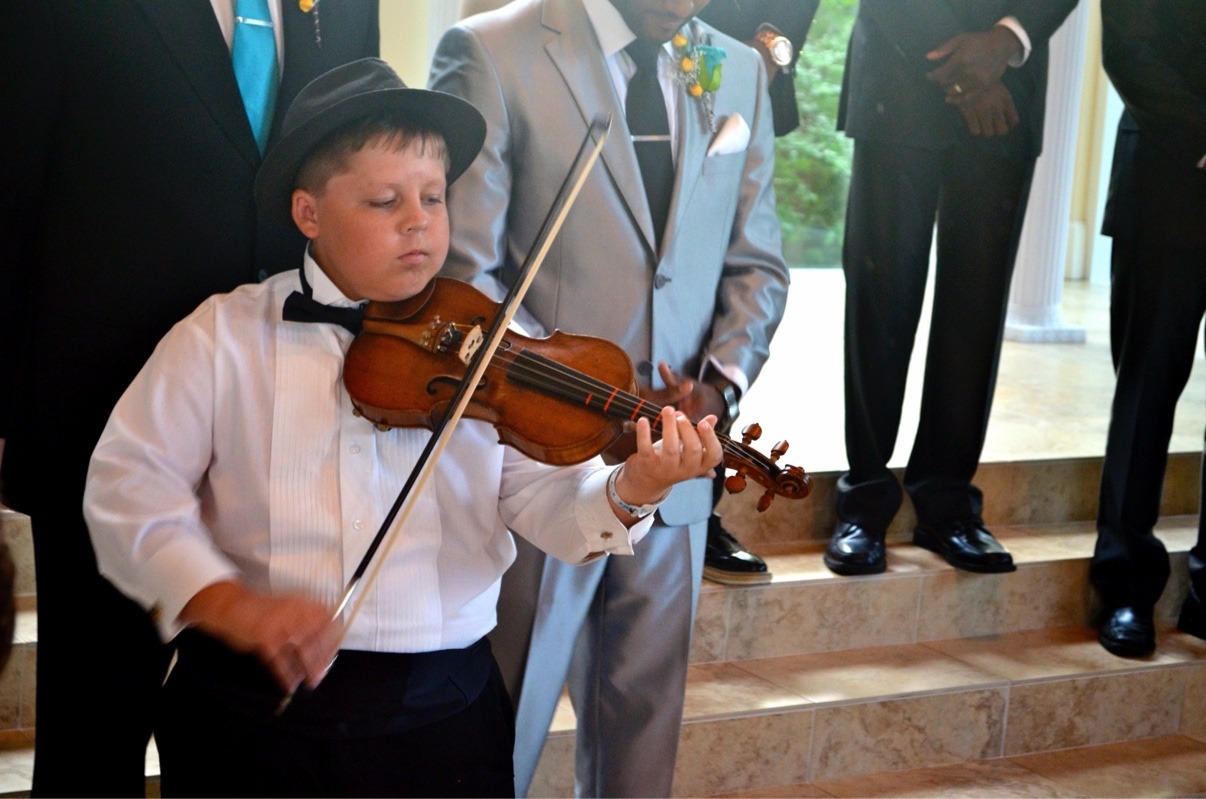 A young Jake playing violin at a wedding