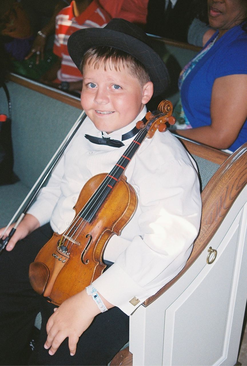 A young Jake smiling with his violin