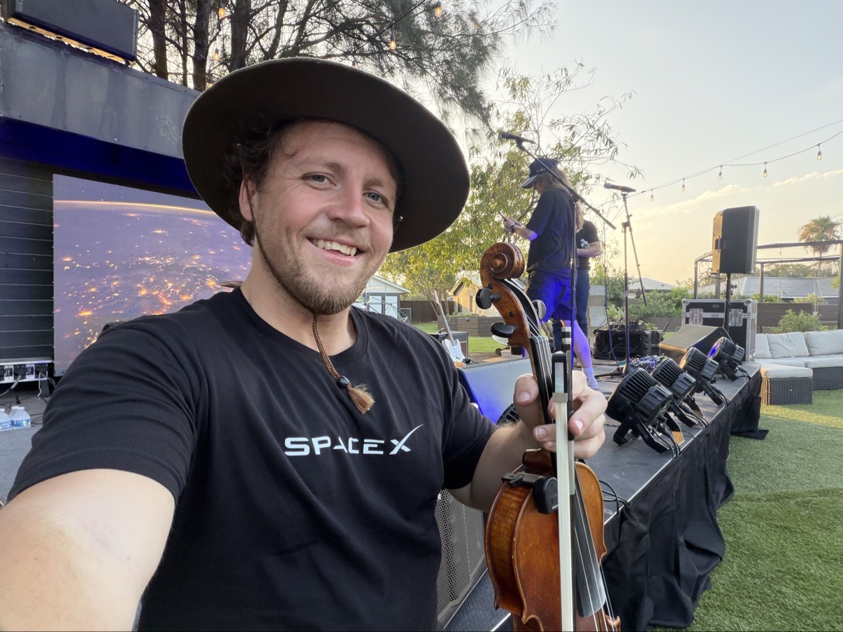 Jake taking a selfie on an outdoor stage in a SpaceX t-shirt
