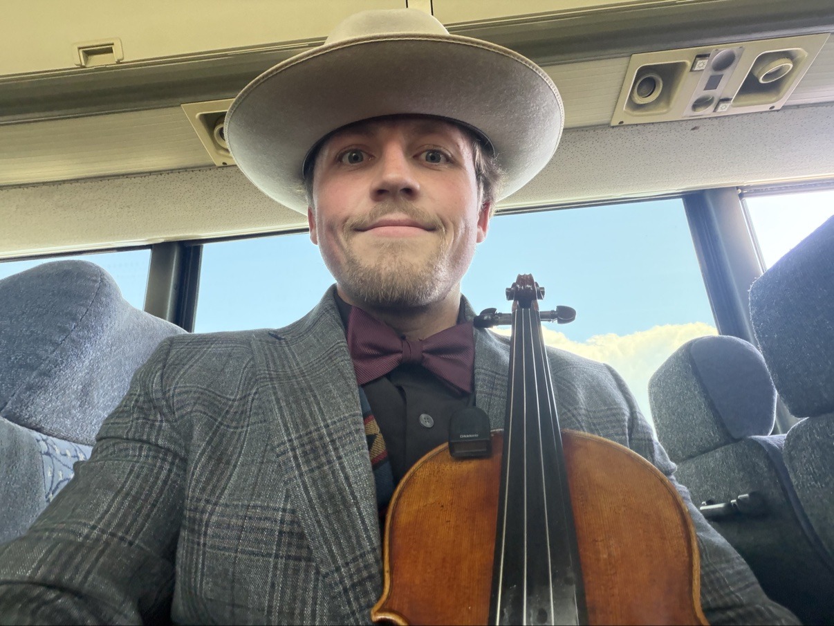 Jake smiling on the tour bus in a suit and bow tie