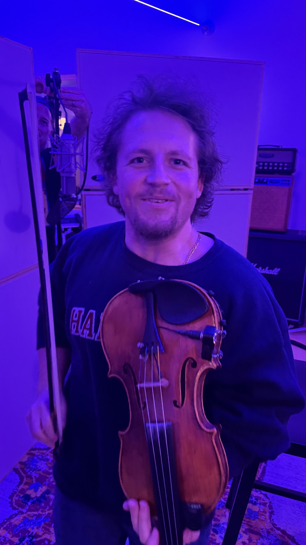 Jake holding his violin in a blue-lit studio session