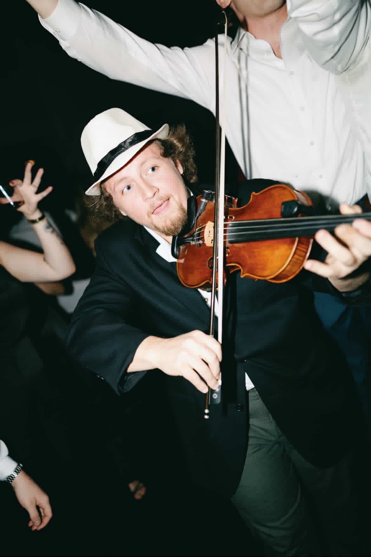 Jake celebrating with friends at a party in a white fedora