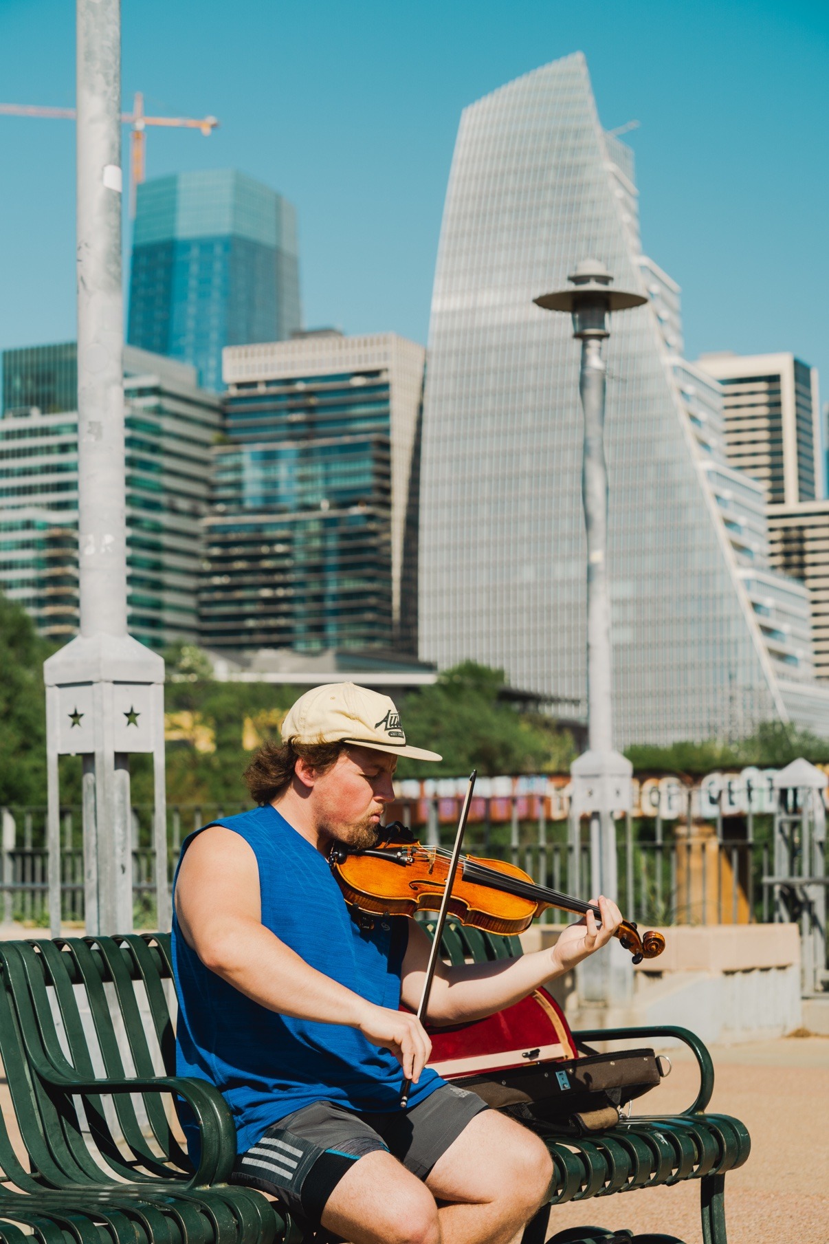 Jake playing violin on a bench in front of a colorful mural in Austin