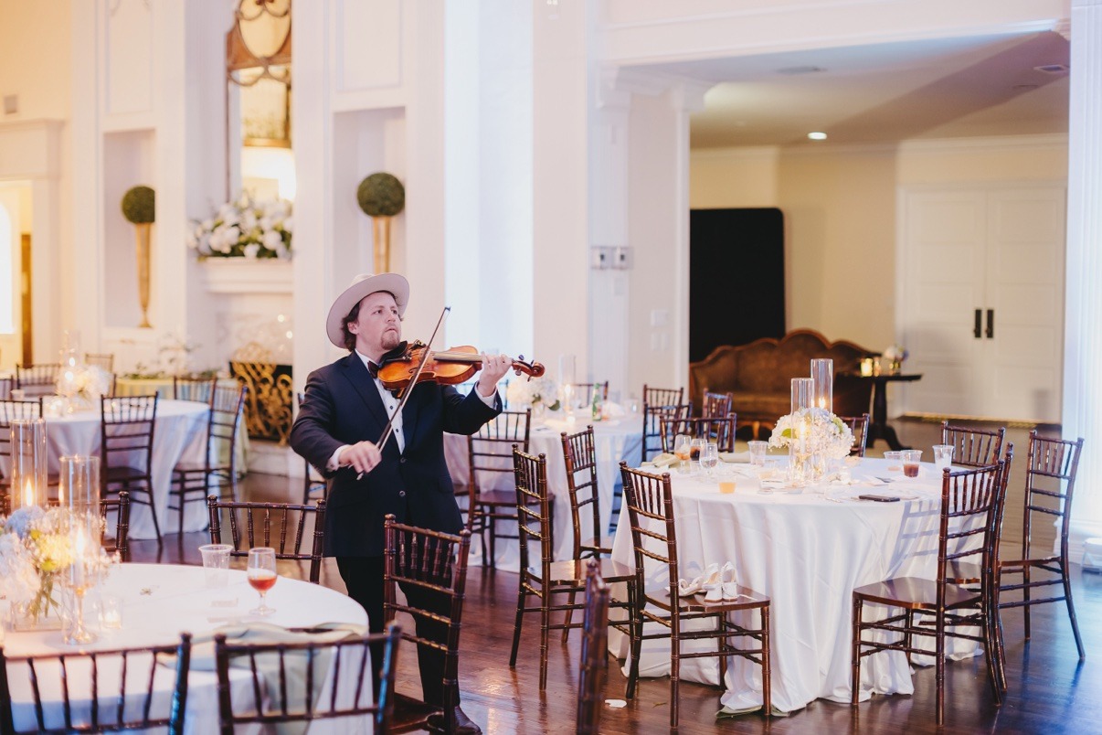 Jake performing violin among the tables at an elegant wedding reception