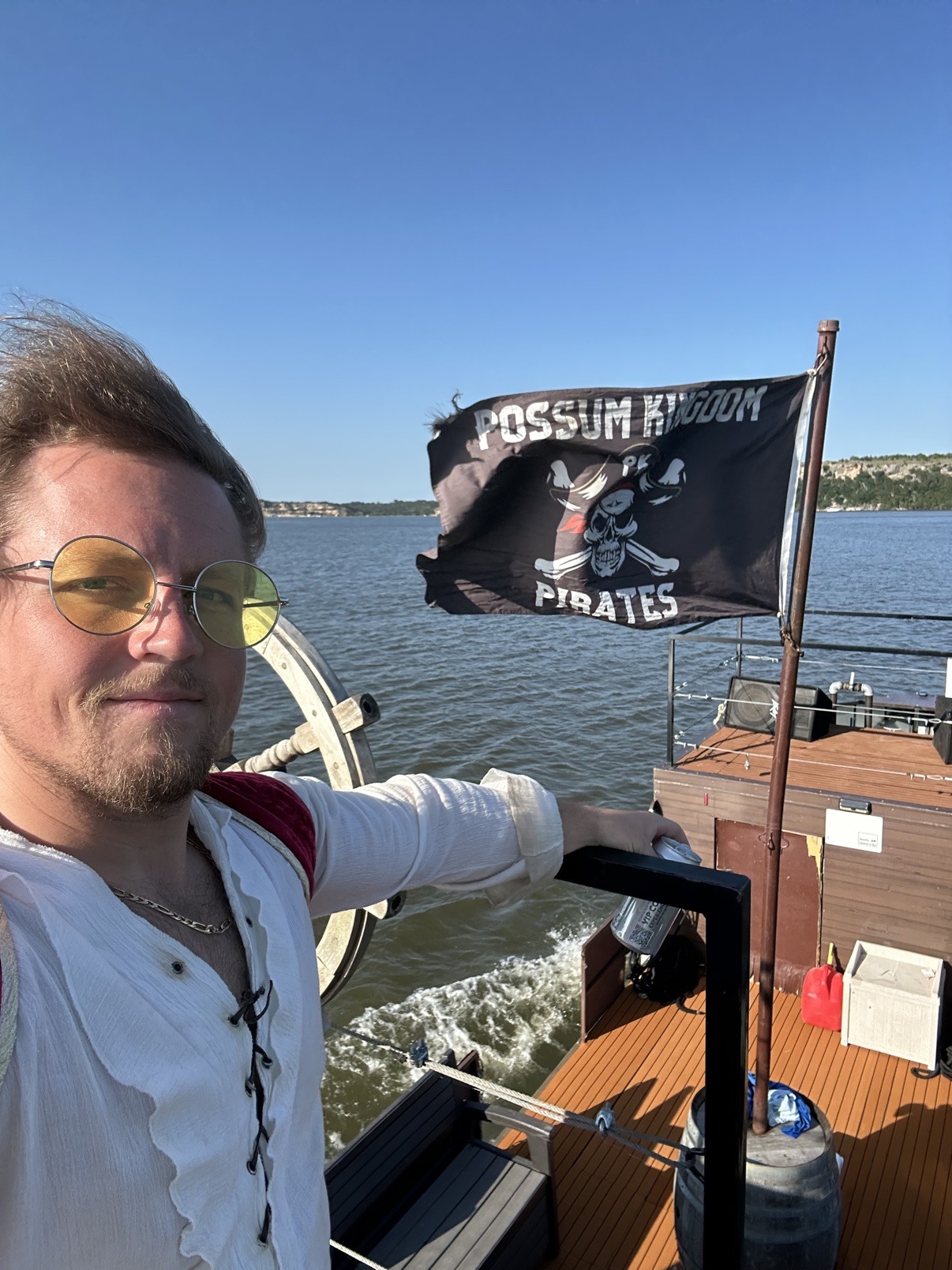 Fiddle aboard the Possum Kingdom pirate ship beside its pirate flag